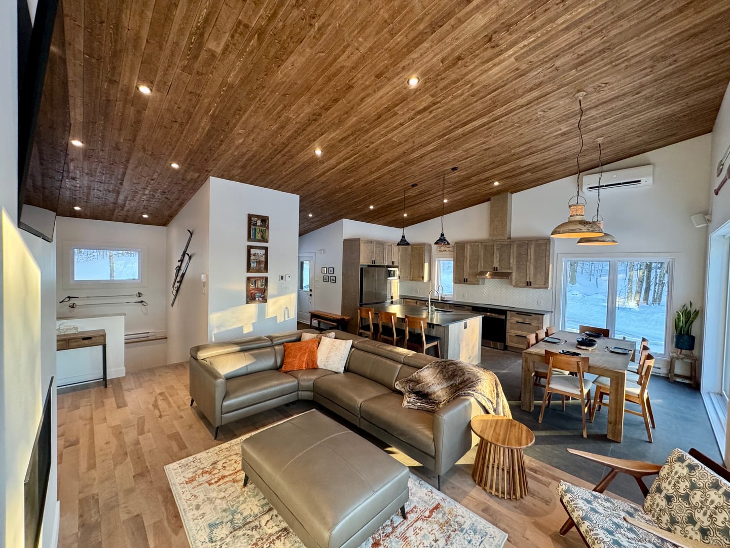 Salon ouvert avec sectionnel cuir, plafond bois et vue cuisine